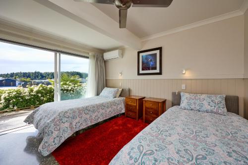 a bedroom with two beds and a large window at Kakatu Retreat Bed & Breakfast in Kaikoura