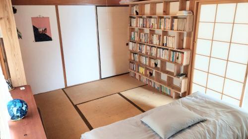 a bedroom with a bed and a book shelf with books at 民泊 inori in Dekiji