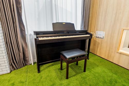 a black piano with a stool next to a window at 親子で遊べるボルダリングやボールプール付きの貸し切りアパート 国立駅徒歩4分 in Kunitachi