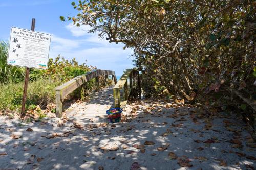 a wooden path leading to a beach with a sign at Villa Fiorō -Bold Luxury 2BR - River & Coastal Vibe in Cocoa Beach