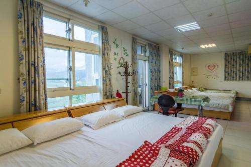 1 Schlafzimmer mit 2 Betten, einem Schreibtisch und Fenstern in der Unterkunft Xinchuan B&B in Dayi