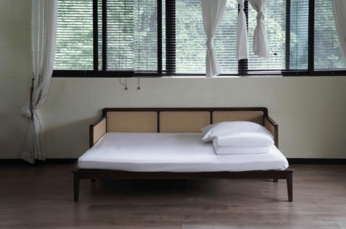 a bed with white sheets and pillows in a room with windows at 青城山坐忘森林疗愈酒店 in Dujiangyan