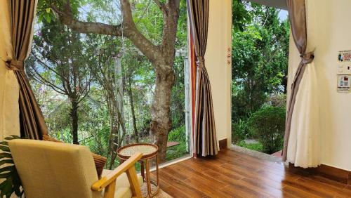 Cette chambre dispose d'une grande fenêtre avec un arbre à l'extérieur. dans l'établissement 3 Tầng Mây Homestay & Coffee, à Xuân Thọ