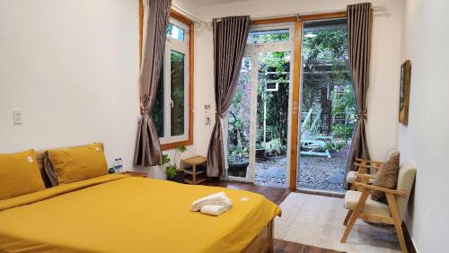 - une chambre avec un lit jaune et une porte coulissante en verre dans l'établissement 3 Tầng Mây Homestay & Coffee, à Xuân Thọ