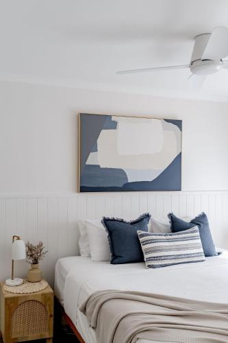 a bedroom with a large bed with blue and white pillows at Sandy Days in Mollymook Beach in Mollymook