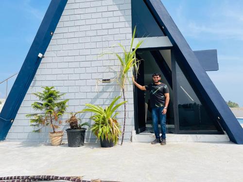 a man standing in the doorway of a building at The A-Frame house in Kūvattūr
