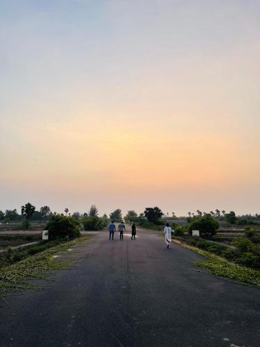 a group of people walking down a road at sunset at The A-Frame house in Kūvattūr
