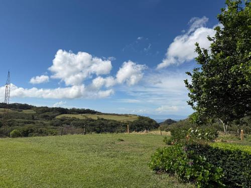 a field of grass with a blue sky and clouds at Campo Azul - Monteverde in Monteverde Costa Rica