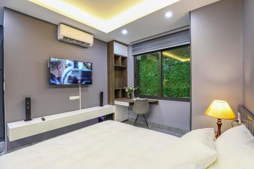 a bedroom with a bed and a tv on the wall at Ben's Signature Hotel and Residence - Hanoi Center in Hanoi