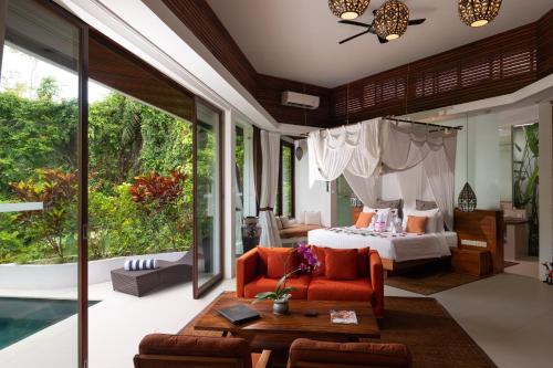 a bedroom with a bed and a living room at Cahaya Indah Villas in Ubud