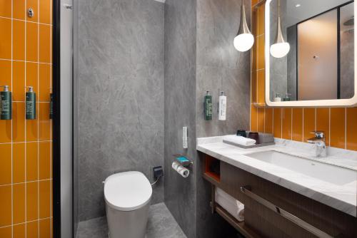 a bathroom with a toilet and a sink and a mirror at Home2 Suite by Hilton Jingdezhen Changnan in Jingdezhen