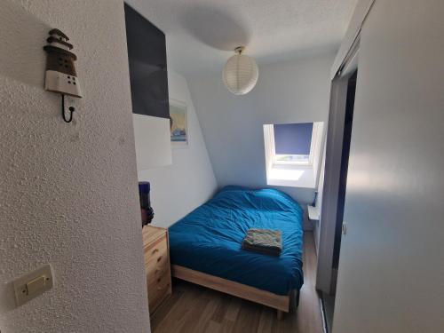 - une petite chambre avec un lit bleu et une fenêtre dans l'établissement Le Cocon Du Lac Villers Sur Mer, à Villers-sur-Mer