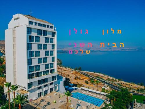 a tall white building next to a body of water at Golan Hotel in Tiberias