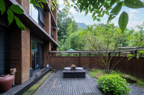 a wooden deck with a bench on the side of a house at 青城山坐忘森林疗愈酒店 in Dujiangyan