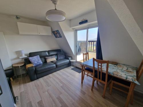 un salon avec un canapé noir et une table dans l'établissement Le Cocon Du Lac Villers Sur Mer, à Villers-sur-Mer