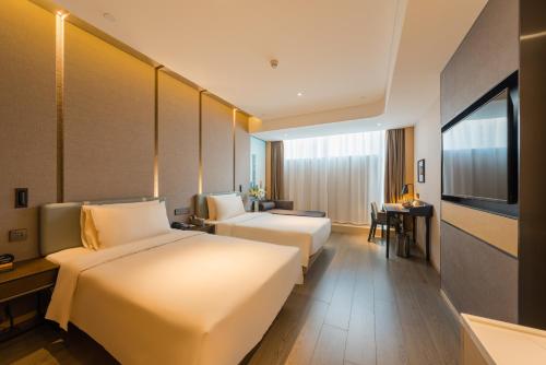 a hotel room with two beds and a flat screen tv at Atour Hotel Beijing You'anmen West Tieying Subway Station in Beijing