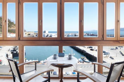 a table and chairs in a room with windows at Katrapona in Getaria