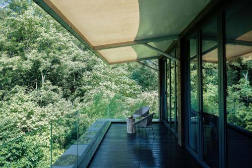 a balcony of a house with a chair on a deck at 青城山坐忘森林疗愈酒店 in Dujiangyan