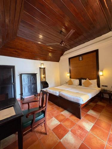 a bedroom with a large bed and a wooden ceiling at Kumarakom Tharavadu - A Heritage Hotel, Kumarakom By Perfect Stays in Kumarakom