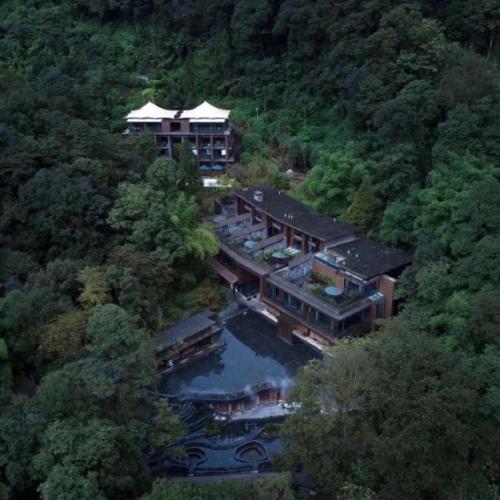 an aerial view of a large house with a lake at 青城山坐忘森林疗愈酒店 in Dujiangyan