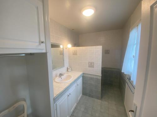 une salle de bain blanche avec un lavabo et un miroir dans l'établissement Maison 5 chambres Cambo les bains 64, à Peyrehorade