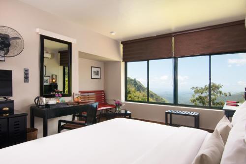 a bedroom with a bed and a desk and a large window at EKHO Ella - A Divine View of Ella Gap in Ella