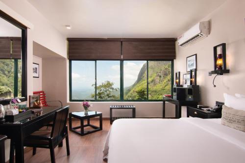 a bedroom with a bed and a desk and a large window at EKHO Ella - A Divine View of Ella Gap in Ella
