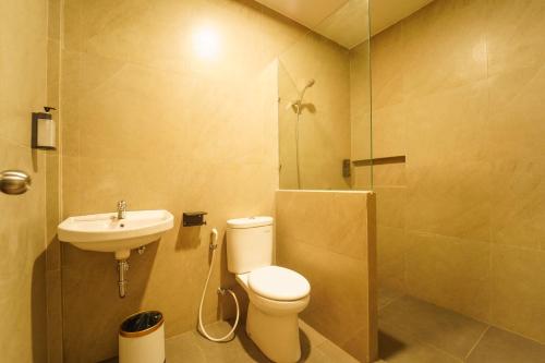 a bathroom with a toilet and a sink and a shower at Evertree Hotel in Balikpapan
