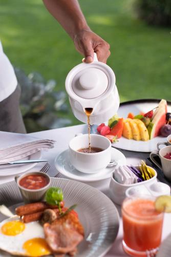 a person pouring coffee into a cup on a table with food at EKHO Ella - A Divine View of Ella Gap in Ella