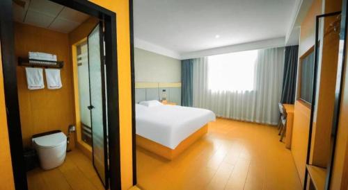 a bedroom with a white bed and a toilet at Shell Hotel Wuhu Jiujiang District Daqiao Town Huashan Road in Wuhu
