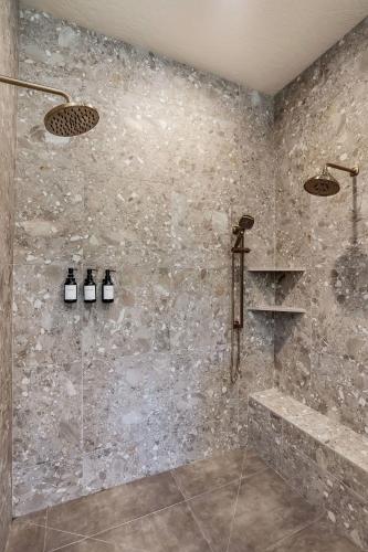 a bathroom with a shower with a stone wall at Violet Retreat in McCall