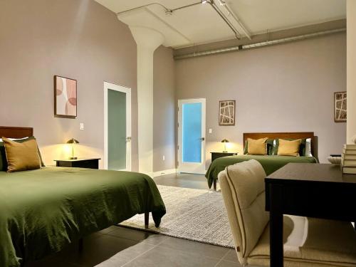 a room with two beds with green comforters at DTLA 2BR Loft with Hot Tub & Rooftop Pool! in Los Angeles