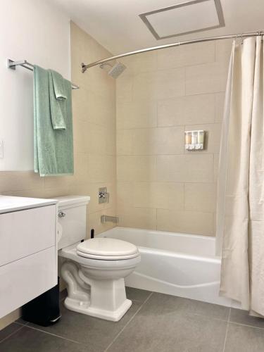 a bathroom with a white toilet and a bath tub at DTLA 2BR Loft with Hot Tub & Rooftop Pool! in Los Angeles