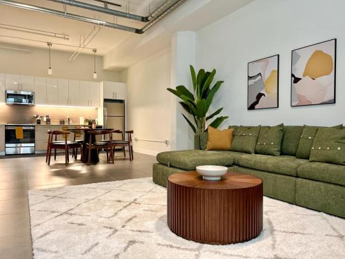 a living room with a green couch and a table at DTLA 2BR Loft with Hot Tub & Rooftop Pool! in Los Angeles