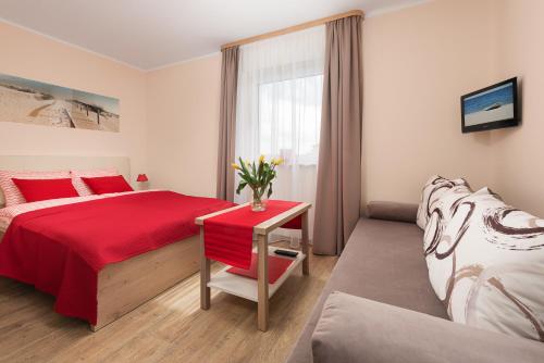 a bedroom with a red bed and a red table at Fajne Apartamenty - Karwia - Blisko Plaży - Komfort i Cisza in Karwia