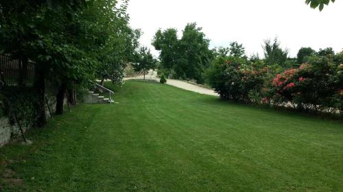 a green grass field with a sidewalk and trees at Relais des Roches in Sona