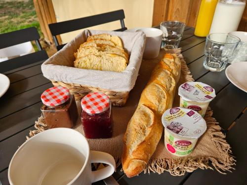 a table topped with a basket of bread and jam at Quiétude & Nature in Le Boupère