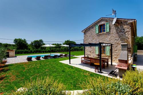 Una casa de piedra con piscina en un patio. en Casa Škitaconka, en Koromačno