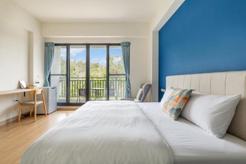 a bedroom with a white bed and a balcony at 北極熊旅店 in Xiaoliuqiu