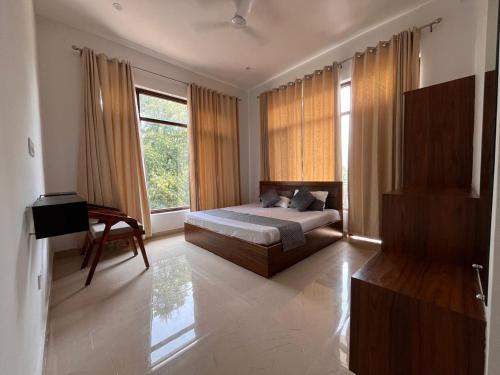 a bedroom with a bed and a desk and window at AeroVale Lodge in Bīr