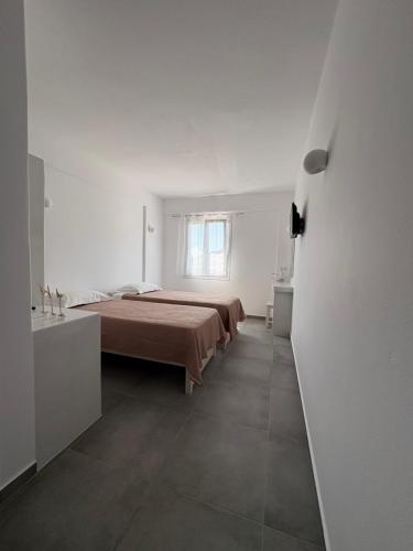 a white room with a bed and a bathroom at Golden Sun in Ios Chora
