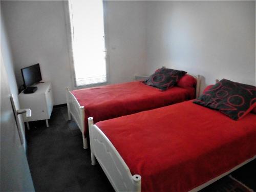 - 2 lits dans une petite chambre avec des draps rouges dans l'établissement bee free, à Montalivet-les-Bains
