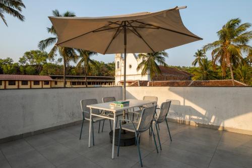 a table and chairs with an umbrella on a roof at SaffronStays Vegas in Nerul