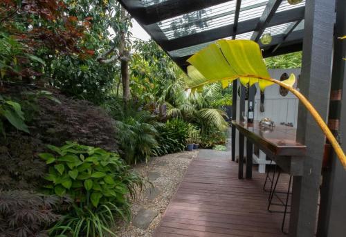 a wooden walkway in a garden with a yellow umbrella at Bungalow Eight - 1930s charm near Pukekura Park in New Plymouth
