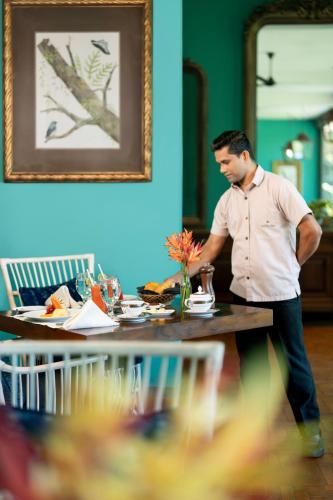 a man standing at a table in a restaurant at Kandy Dendrobium House in Kandy