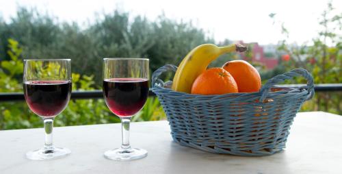 two glasses of wine and a basket of fruit on a table at Elia Houses in Koutsounari