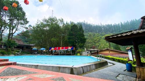 een groot blauw zwembad met een berg op de achtergrond bij Guci Heritage Hotel in Tuwel