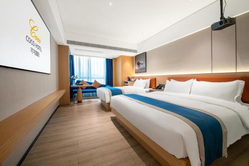 a hotel room with two beds and a television at 广州白云国际机场可可Coco酒店-广交会期间展馆穿梭巴士 in Huadu