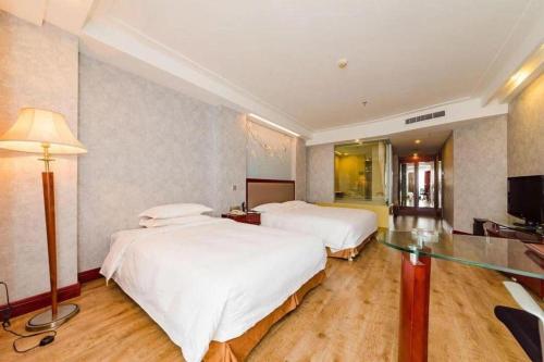 a hotel room with two beds and a television at Junyu Grand Hotel Qinhuangdao in Qinhuangdao