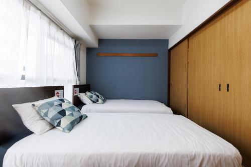 two beds in a small bedroom with blue walls at Grande Famille Shimanouchi Dotonbori Condo in Osaka